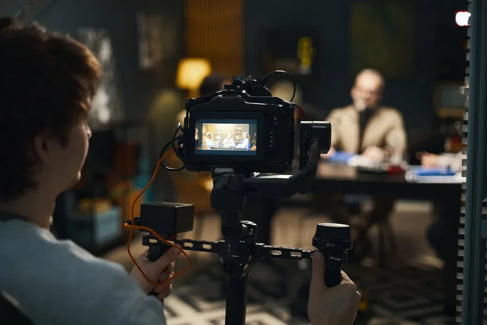 Camera operator filming a podcast interview on a professional monitor