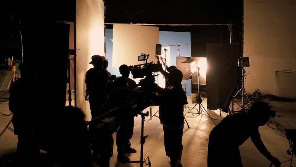Film crew silhouetted while setting up lighting equipment on set